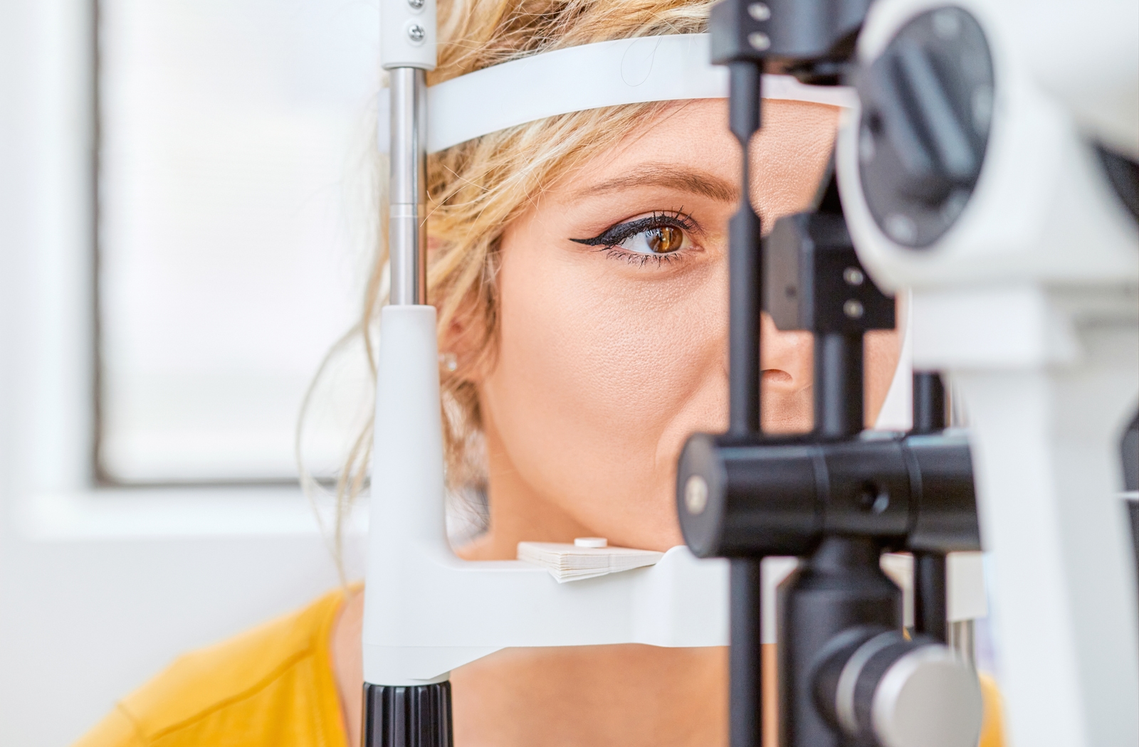 A woman at her optometrist undergoing a slit lamp test to check her vision at her regular eye exam
