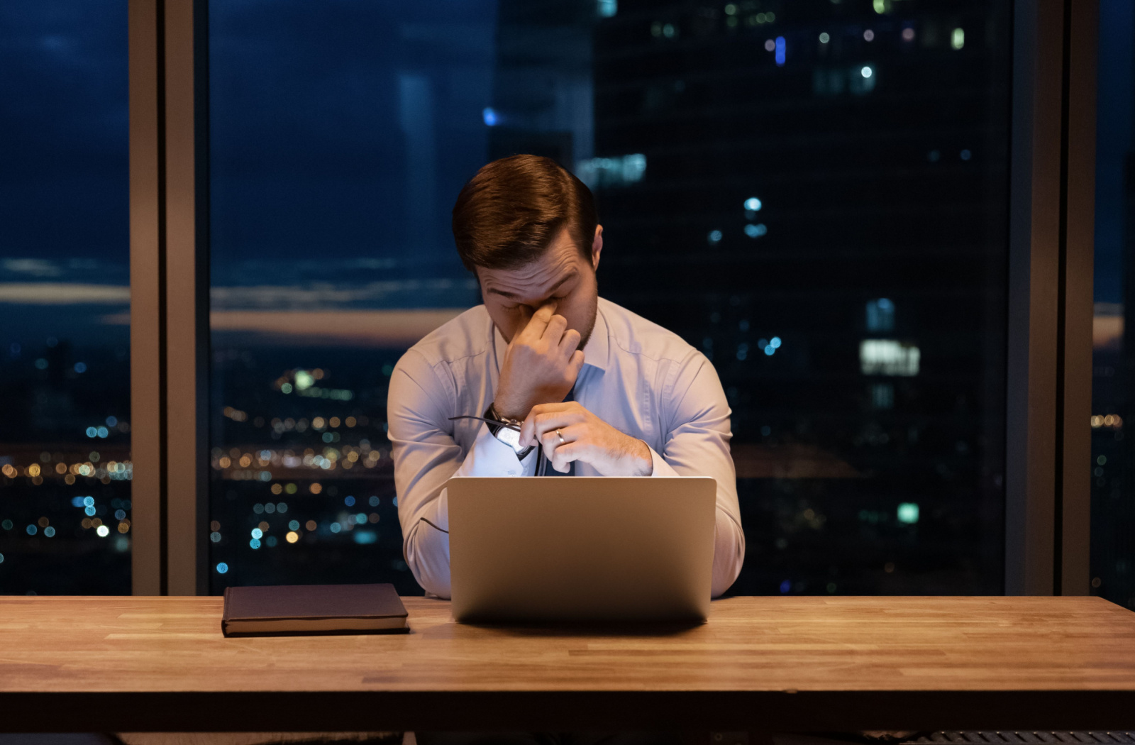 A professional-looking young man rubbed both of his eyes after a long exposure to his laptop screen.