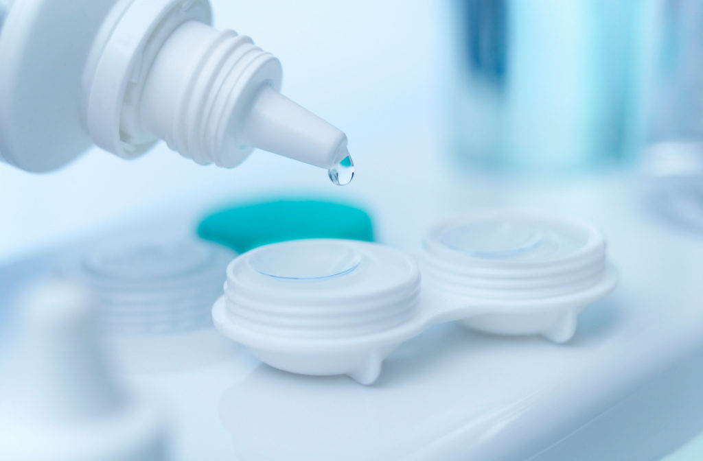 Close up of contact lens solution being applied to contact lenses in their container