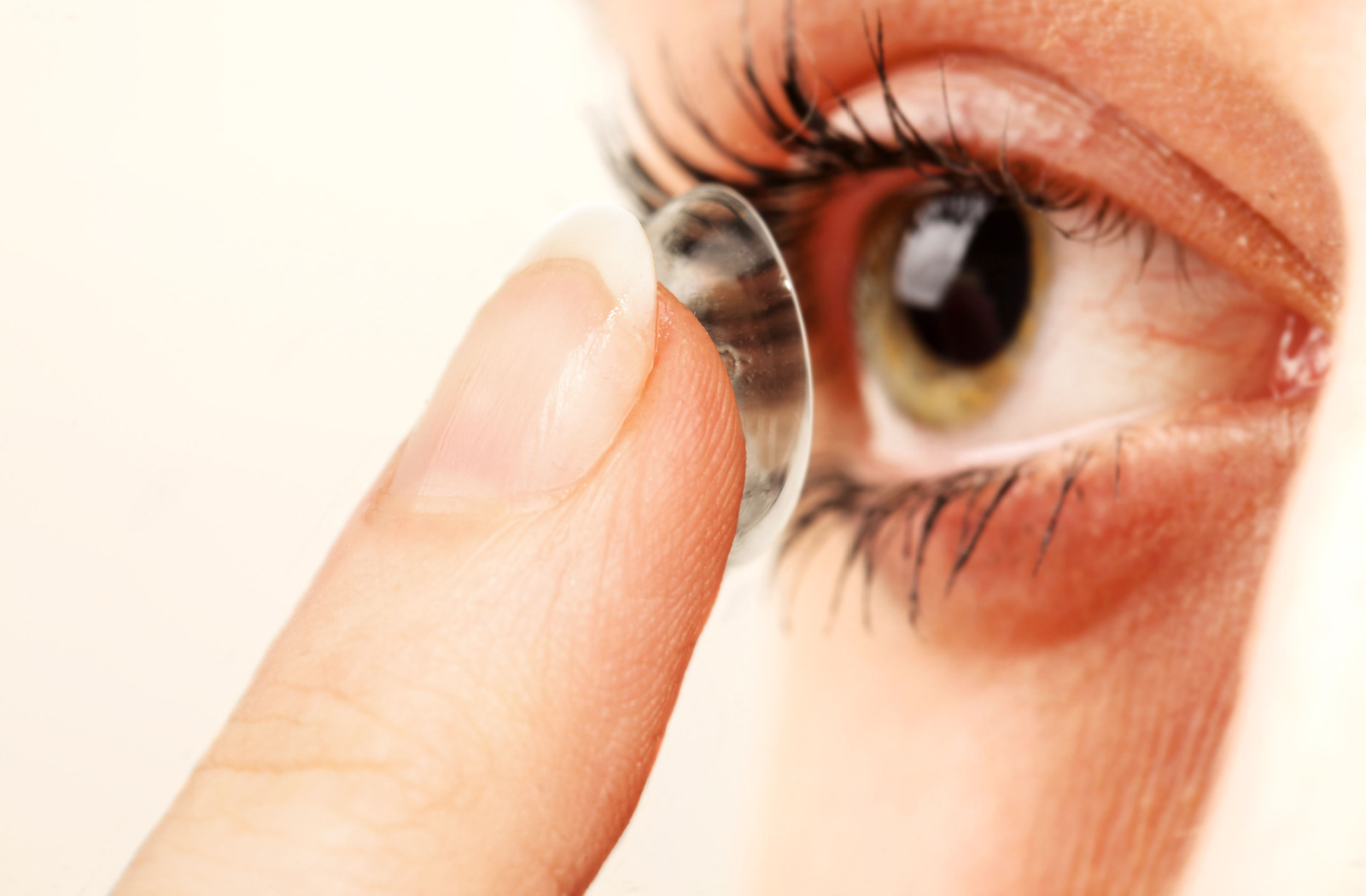 Close up of a patient applying a contact lens to their right eye