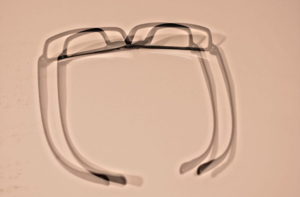 A pair of glasses are slightly blurry showing two glasses instead of one, outlining what an astigmatism looks like.
