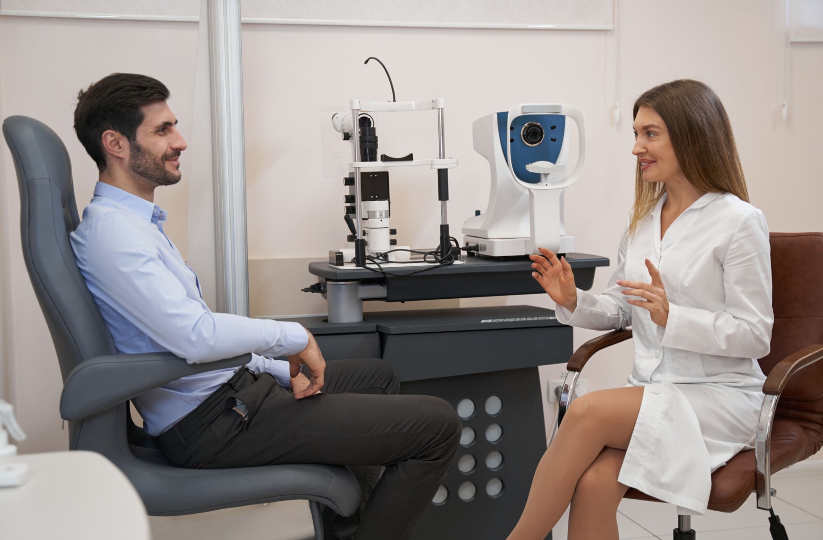 A female optometrist talking to a male patient in an optometry clinic about how to prevent eye rubbing.
