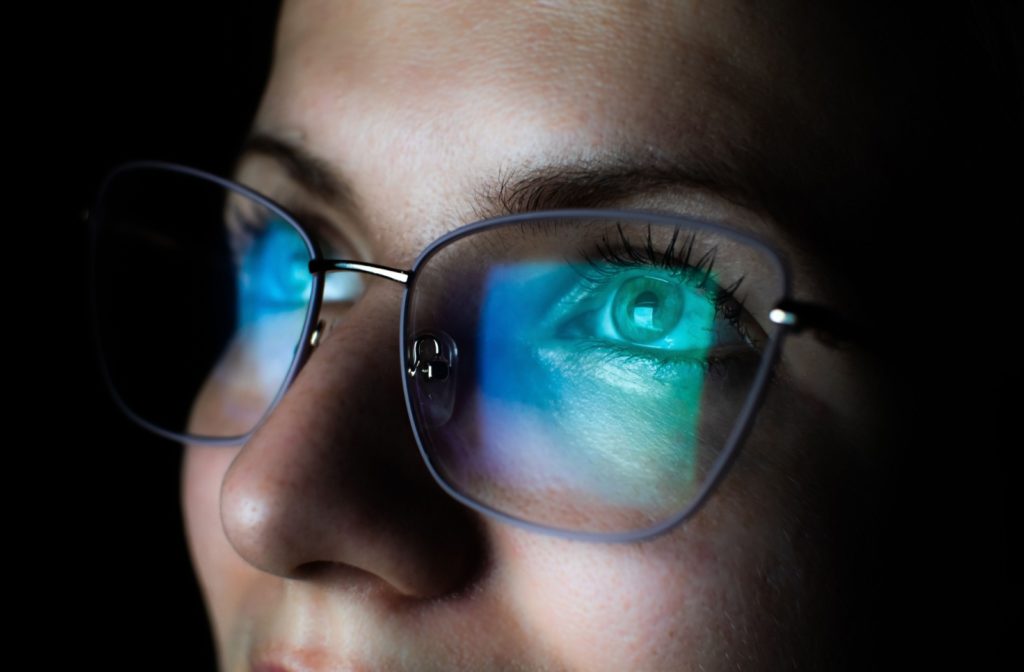 Close up of a woman's face with a computer screen reflected in her blue light glasses