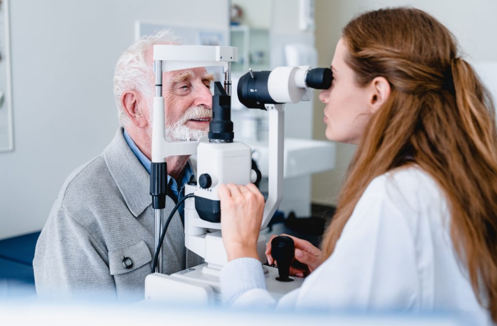 Eye doctor examining a senior patient's eye with a slit lamp.