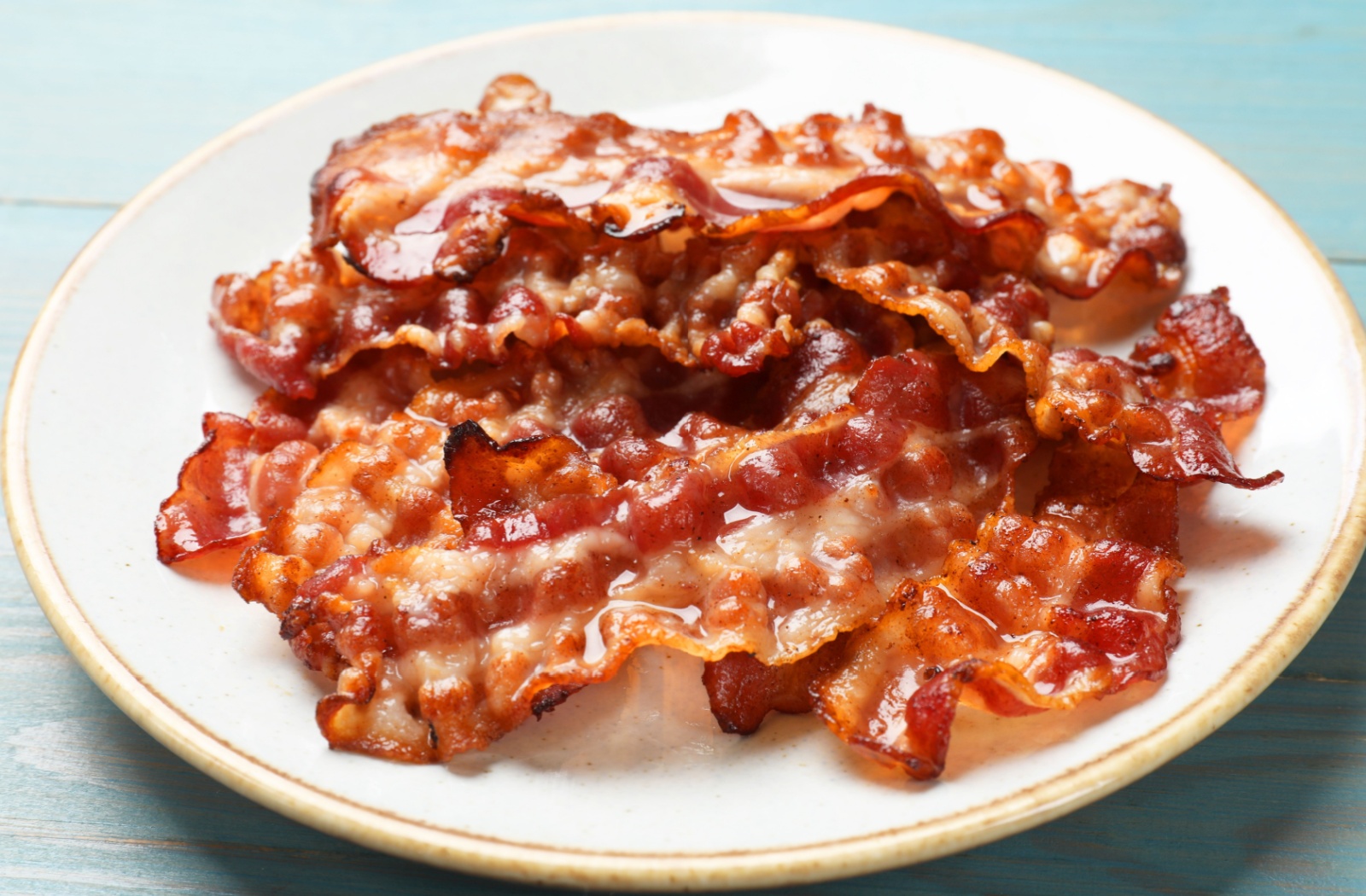 Pieces of cooked bacon piled on top of a plate
