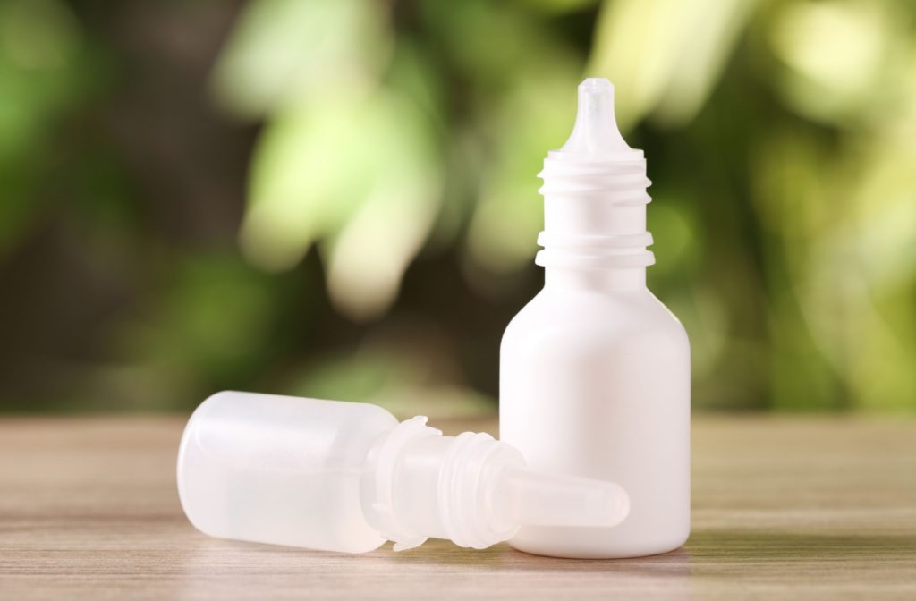 An image of 2 eye drop bottles on a table, 1 is tipped over and the other is standing up.