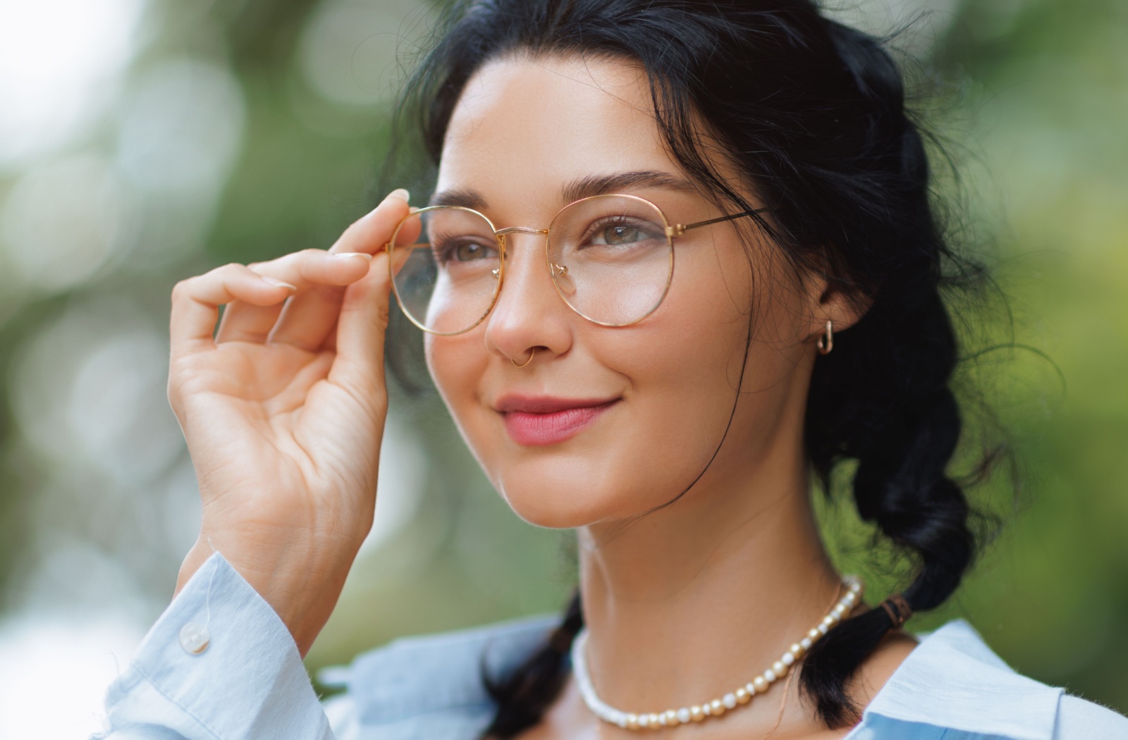 A young brunette woman adjusts her new glasses.