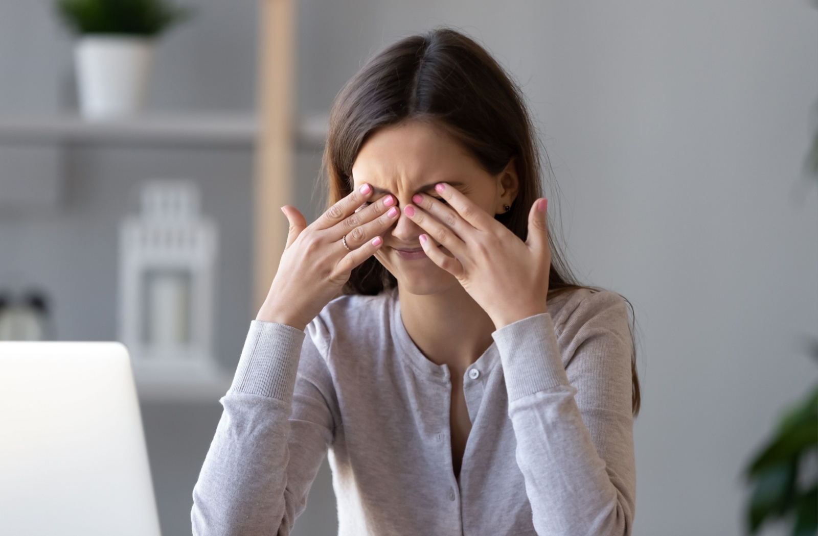 A woman rubs at her eyes from digital eye strain.
