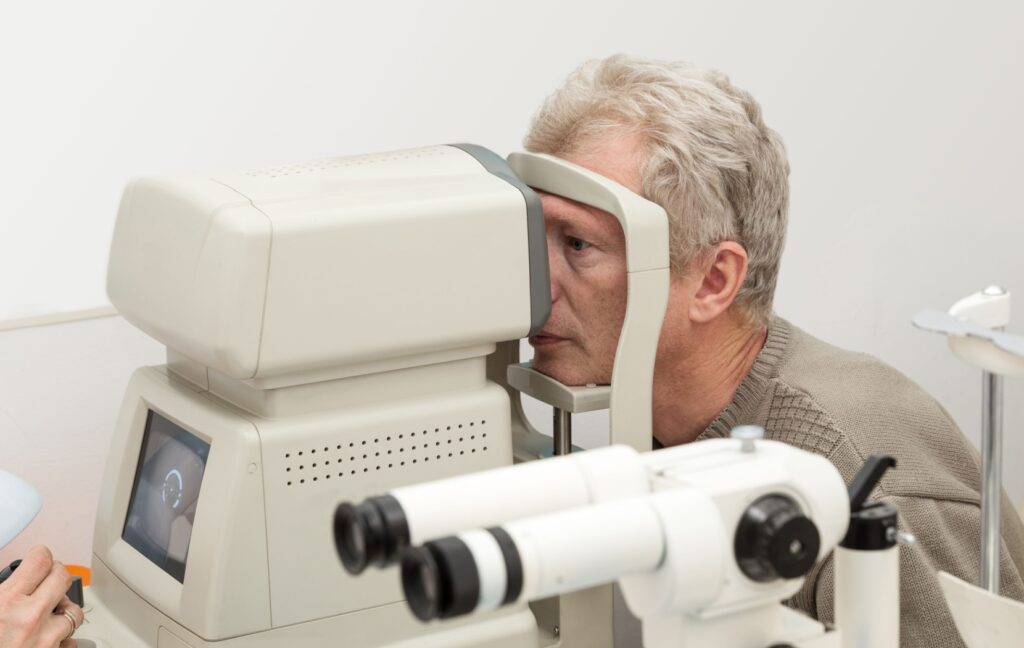 An optometrist examines the back of a middle-aged adult's retina to monitor their eye for signs of diabetic retinopathy.
