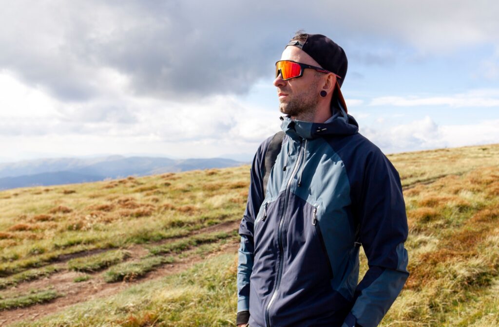 An adult wearing sunglasses to protect their eyes while on a hike.