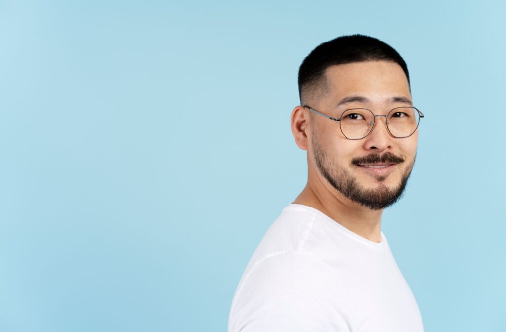 A portrait of a smiling adult wearing round eyeglasses.