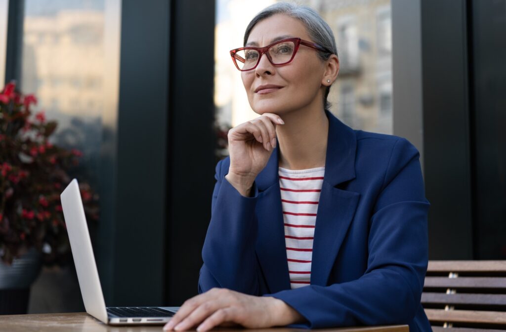 A smiling mature professional wearing sleek cat-eye glasses.