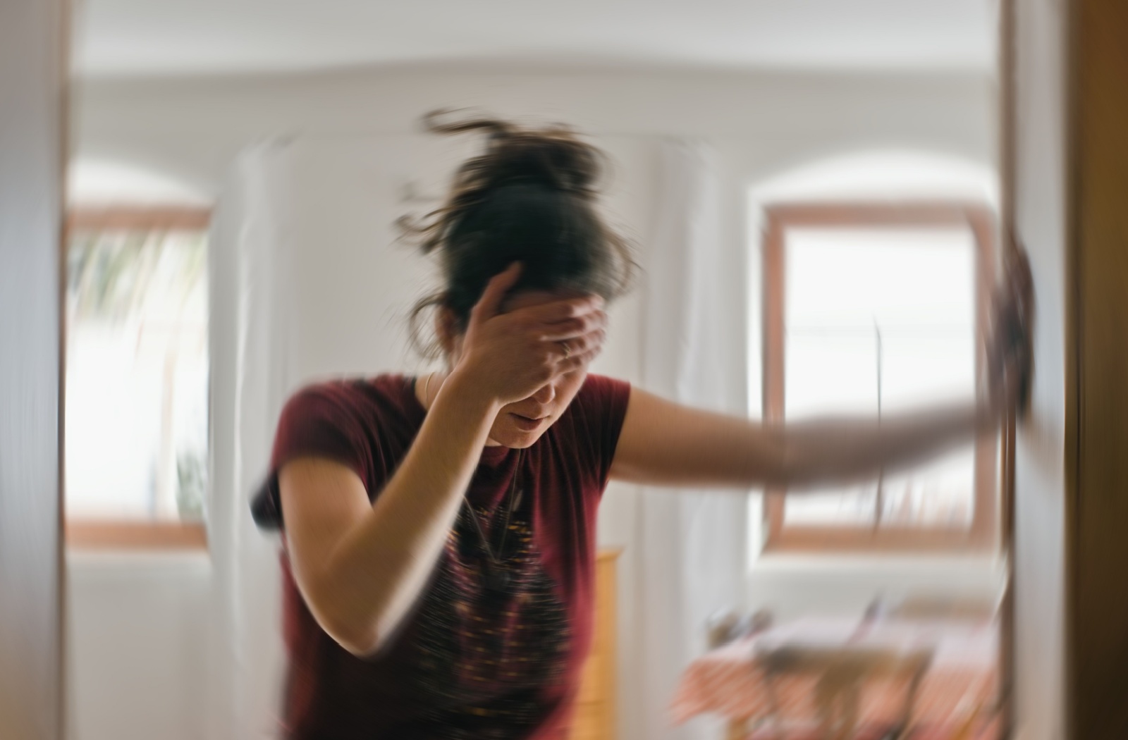 A blurry image of a woman with vertigo holding herself up using a wall.