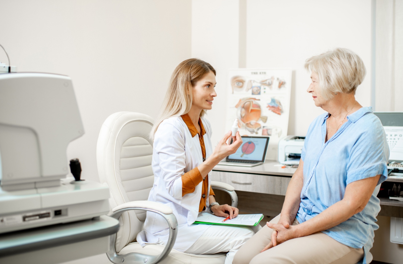 Optometrist showing older female patient a bottle of eye drops.